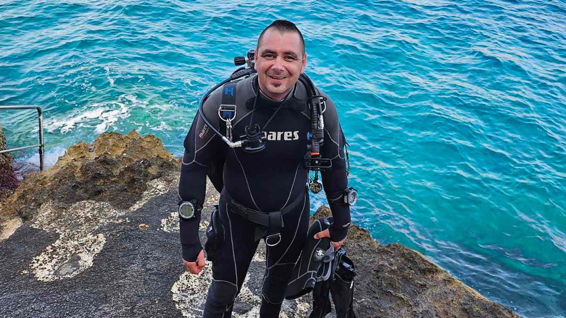 Csikós István búvárruhába áll a vízparton.
